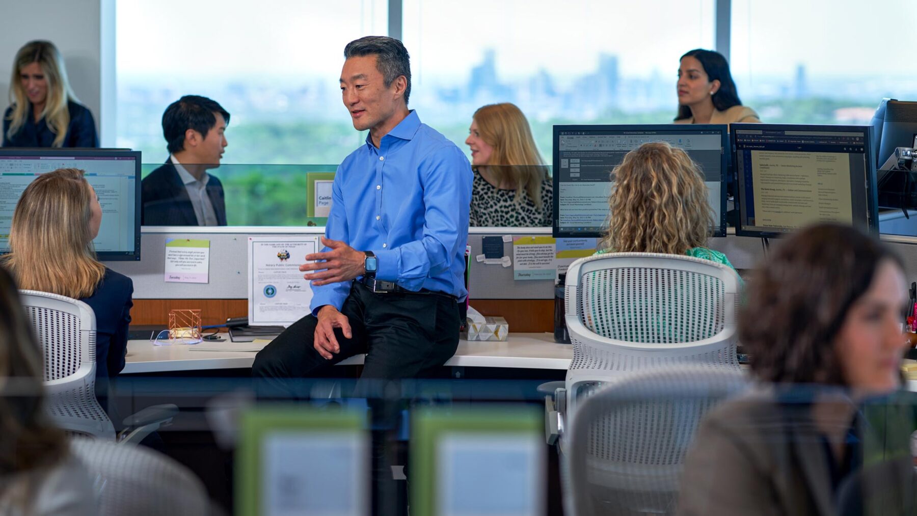 Dimensional employees collaborating at their desks.